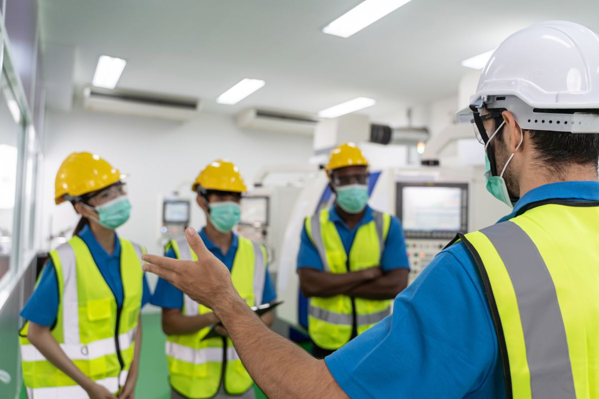 Employés avec des casques et masques qui reçoivent des consignes de sécurité au travail